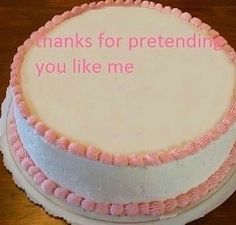 a white cake with pink icing and words on the top that says thanks for pretending you like me