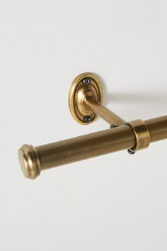 an old fashioned brass toilet paper holder on a white wall with a gold handle and pull bar