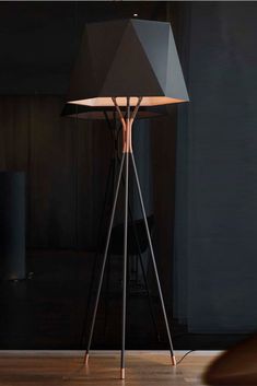 a floor lamp sitting on top of a hard wood floor next to a black wall