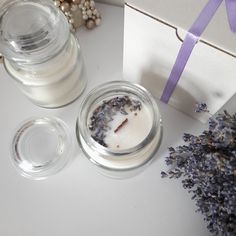 two jars with candles and lavender flowers next to a gift box