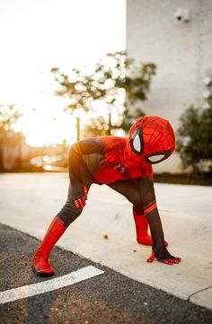 a person in a spider man costume is standing on one leg with his hands behind his head