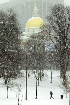 a person is walking through the snow in front of a building with a dome on top