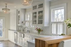 a large kitchen with white cabinets and wooden counter tops, along with a center island