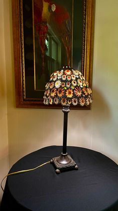 a lamp sitting on top of a black table next to a framed painting in a room