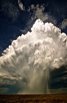 a large cloud is in the sky above a field