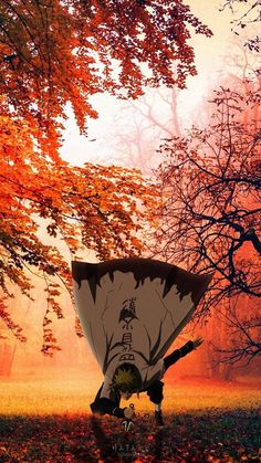 a person holding an umbrella in the middle of a field with fall leaves on it