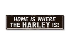 a black and white sign that says home is where the harley is on it's side