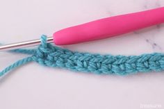 the crochet stitch is being worked on with a pink crochet hook