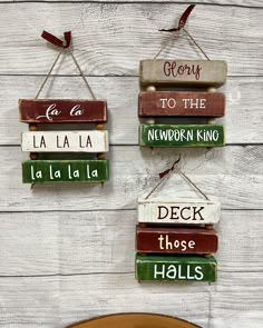 three wooden signs hanging on the side of a white wood wall with words written in different languages