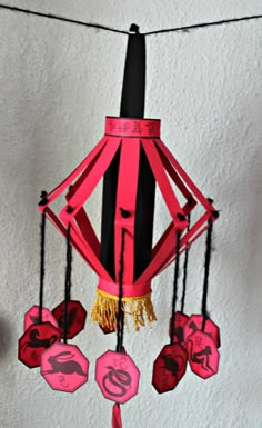 a pink and black wind chime hanging from a string with chinese symbols on it