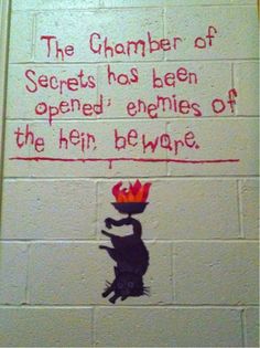 graffiti on the side of a white brick wall depicting a cat with a red crown