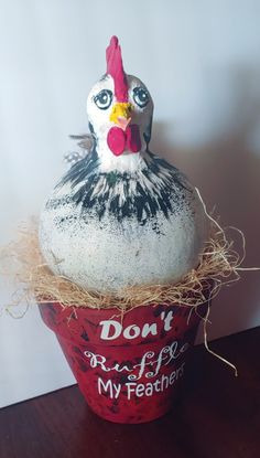 a fake chicken sitting on top of a red bucket