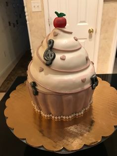 a large cupcake cake sitting on top of a wooden table next to a white door