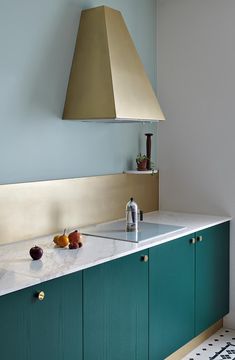 a kitchen with green cabinets and gold hood