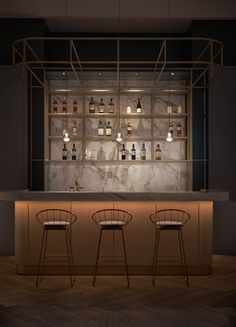 two bar stools sitting in front of a counter with bottles on it and lights hanging from the ceiling