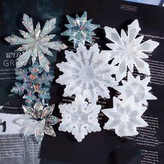 three snowflakes are on display in a window with an open book behind them