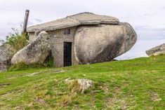 a rock house on top of a hill with grass and rocks in the foreground