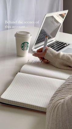 a person holding a pen and writing on a notebook with a starbucks cup in front of them