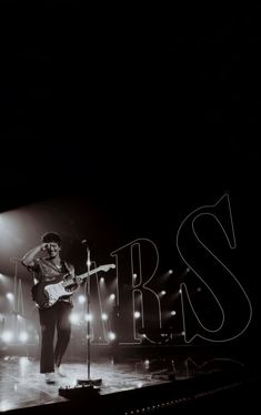 a black and white photo of a person on stage with a guitar in front of him