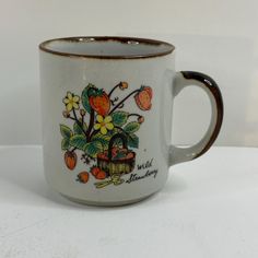 a coffee mug with fruit and flowers painted on the inside is sitting on a white surface