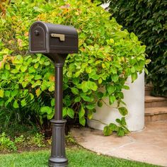 a mailbox sitting in the grass next to some bushes