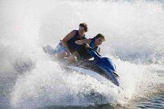 two people riding on the back of a jet ski while being pulled by a boat