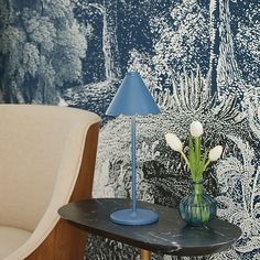 a blue lamp sitting on top of a table next to a vase with flowers in it