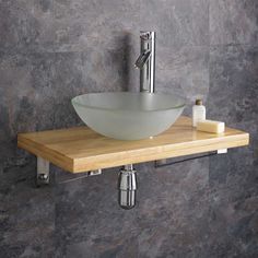 a white bowl sink sitting on top of a wooden shelf next to a faucet