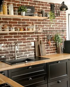 a kitchen with brick wall and wooden counter tops, black appliances and open shelving