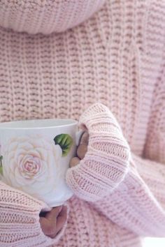 a close up of a person holding a coffee cup in their hands with flowers on it