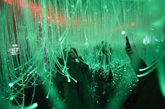 two people standing in front of a green light with their hands up to the ceiling