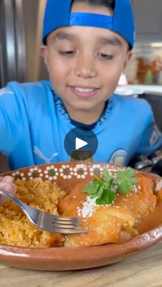 a young boy sitting at a table with a plate of food