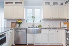 a clean kitchen with white cabinets and stainless steel dishwasher, stove top oven and sink