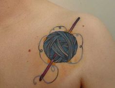 a ball of yarn and knitting needles tattoo on the back of a woman's shoulder