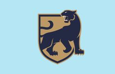 a blue and brown logo with a black lion on it's chest, in front of a light blue background