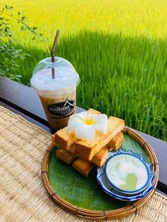 a cup of coffee and some food on a plate with grass in the back ground