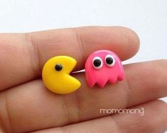 two little paco monster earrings sitting on someone's finger