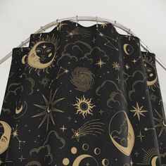 a shower curtain with gold stars and moon designs on black fabric, hanging from a metal rod