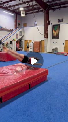 a person on a trampoline doing tricks in a room with blue carpet and walls