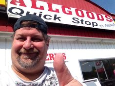 a man giving the thumbs up sign in front of a building that says all good's quick stop