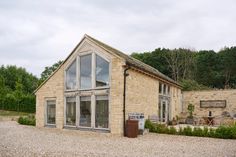 a stone building with large windows on the outside and gravel ground in front of it