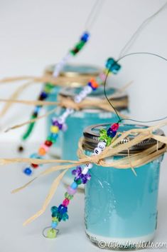 three jars filled with blue liquid and colorful beads