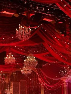 an elaborately decorated banquet hall with chandeliers and red drapes on the ceiling