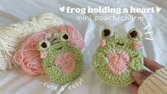 two crocheted frog purses with eyes and nose are on a bed next to balls of yarn