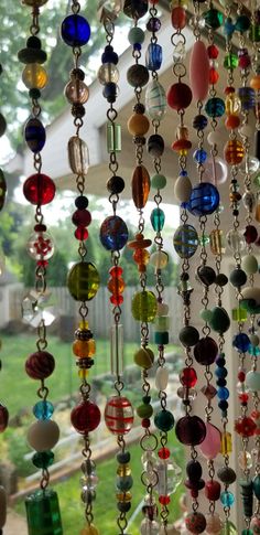 many different colored glass beads hanging from a window