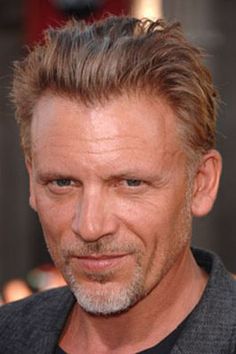 a close up of a person wearing a suit and tie with a smile on his face