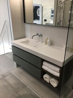 a bathroom with a sink, mirror and towels on the counter in front of it