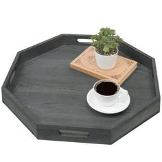 a small potted plant sitting on top of a wooden tray next to a cup of coffee