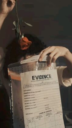 a person holding a paper with the word evidence written on it and a rose in their hand