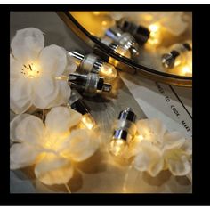 some white flowers and lights in front of a mirror